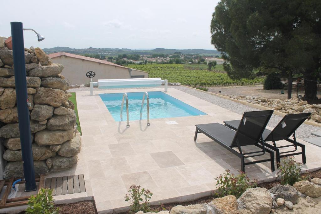 une piscine avec deux chaises et une balançoire dans l'établissement La Cabanne du Vigné, à Saint-Pargoire 5 autres photos