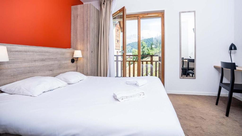 une chambre d'hôtel avec un lit blanc et une fenêtre dans l'établissement Villages Clubs du Soleil - OZ EN OISANS, à Oz