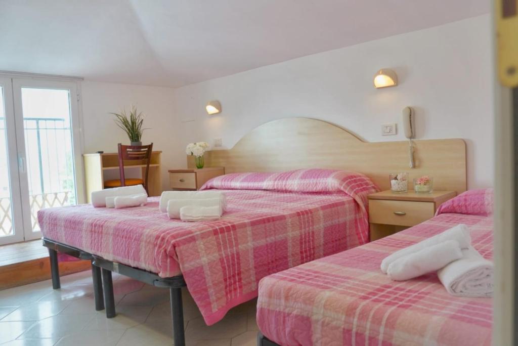- une chambre avec 3 lits avec des draps roses et blancs dans l'établissement Hotel Malibù Mare, à Rimini