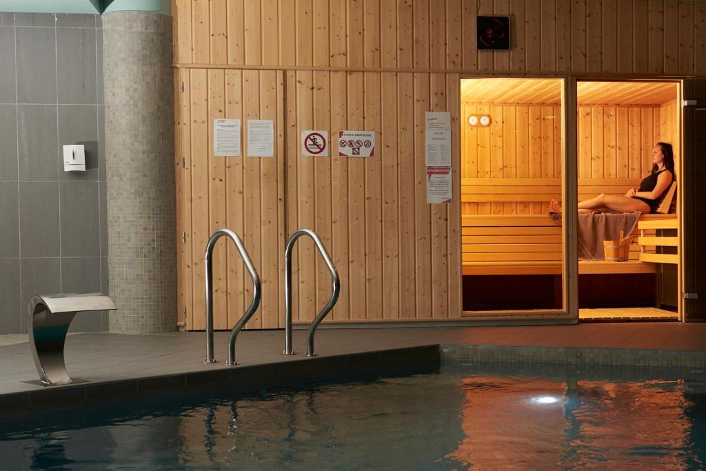 - une piscine avec une femme assise sur un lit dans l'établissement Villages Clubs du Soleil - OZ EN OISANS, à Oz