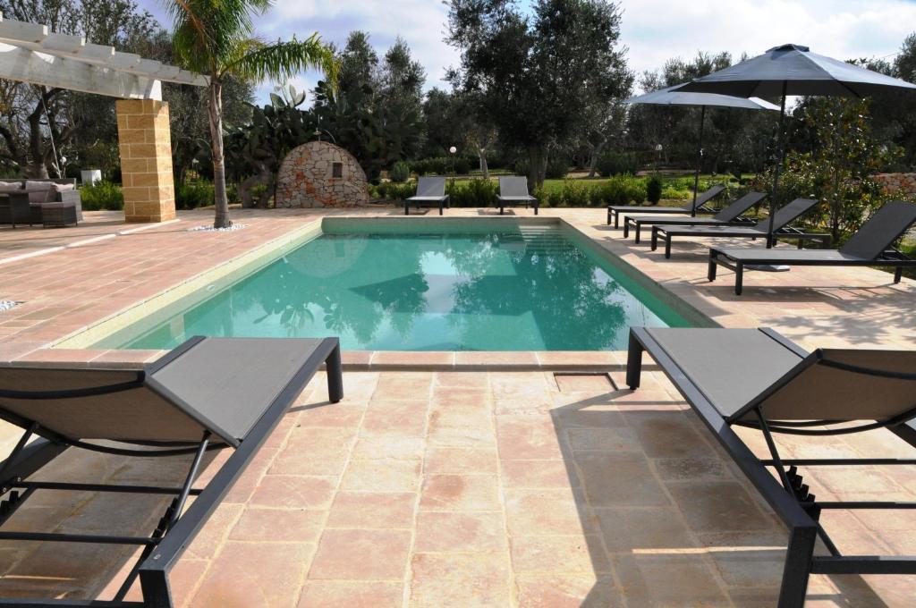 une piscine avec des chaises et un parasol dans l'établissement Oasi Temerano, à Seclì