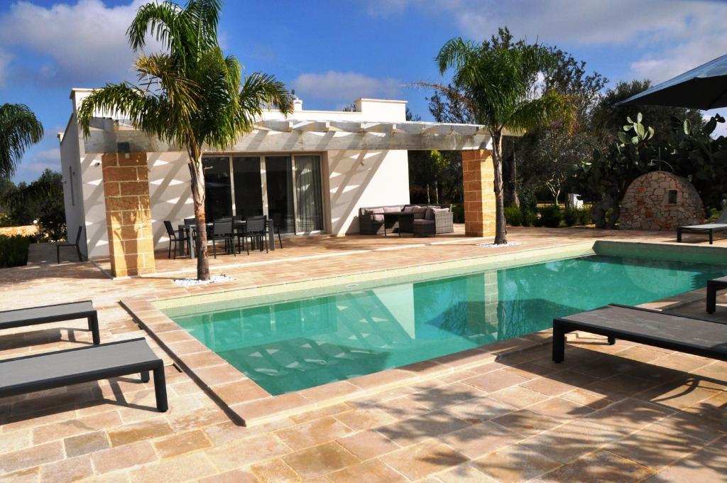 une piscine avec deux chaises et une maison dans l'établissement Oasi Temerano, à Seclì