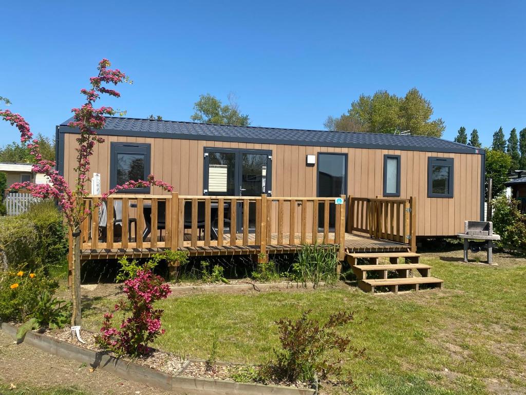 une petite maison dans une cour avec une terrasse dans l'établissement Camping-Caravaning de la Mollière, à Groffliers