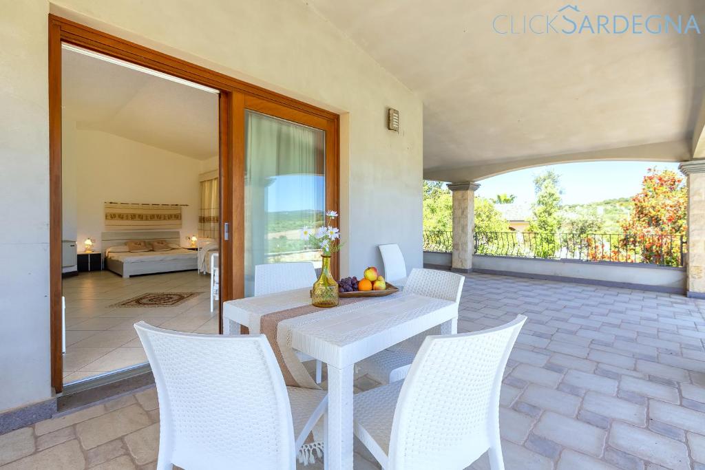 une table blanche et des chaises sur une terrasse dans l'établissement Villa Janas Luxury Villa surrounded by large park, swimming pool, parking and Wifi, à Alghero