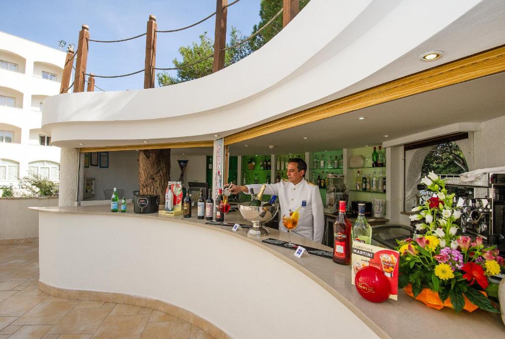 un homme debout derrière un bar avec un verre dans l'établissement Ecoresort Le Sirene - Caroli Hotels, à Gallipoli