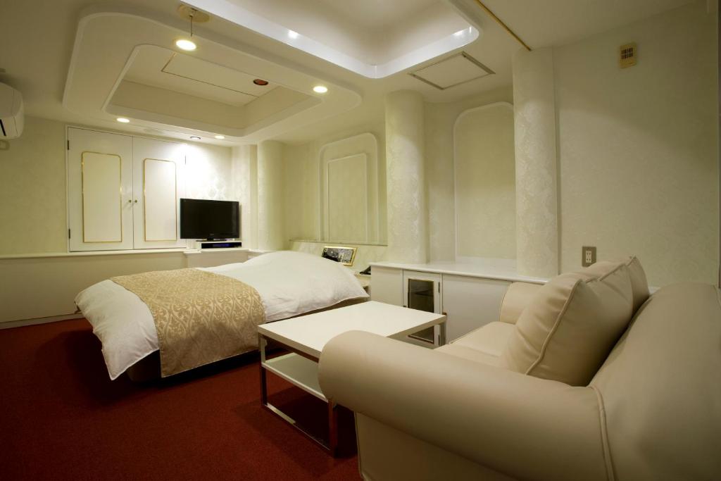 une chambre avec un lit, un canapé et une chaise dans l'établissement Hotel Jay -Adult Only-, à Osaka