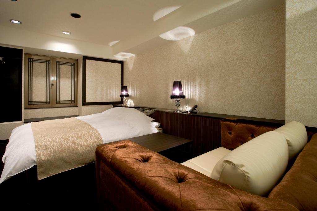 une chambre d'hôtel avec un lit et un canapé dans l'établissement Hotel Jay -Adult Only-, à Osaka