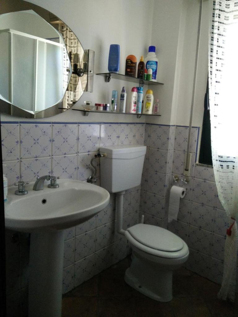 une salle de bain avec toilettes, lavabo et miroir dans l'établissement Mamma Arancia, à Pedagaggi