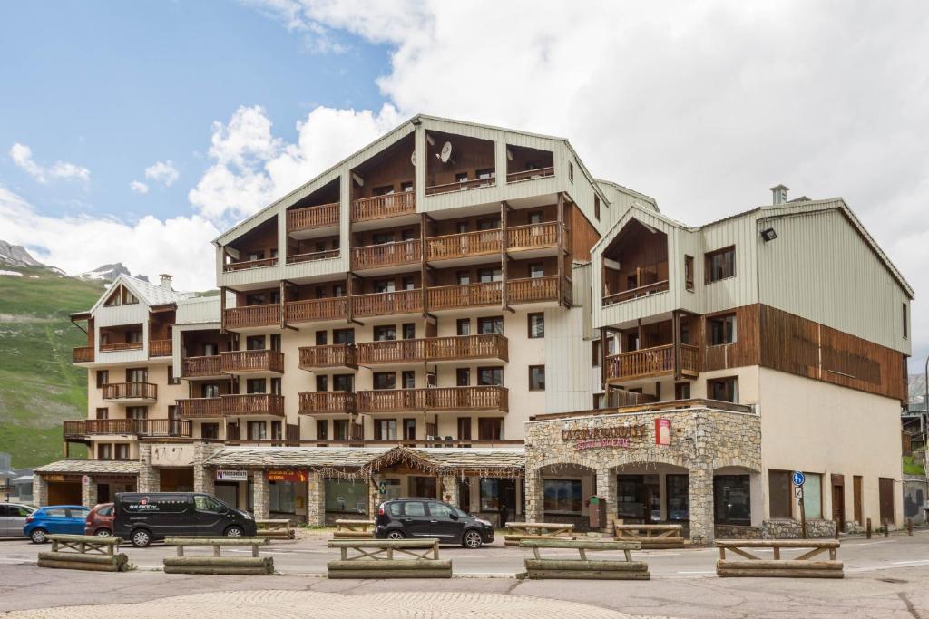 un grand bâtiment avec des voitures garées devant dans l'établissement Vacancéole - Le Borsat IV, à Tignes