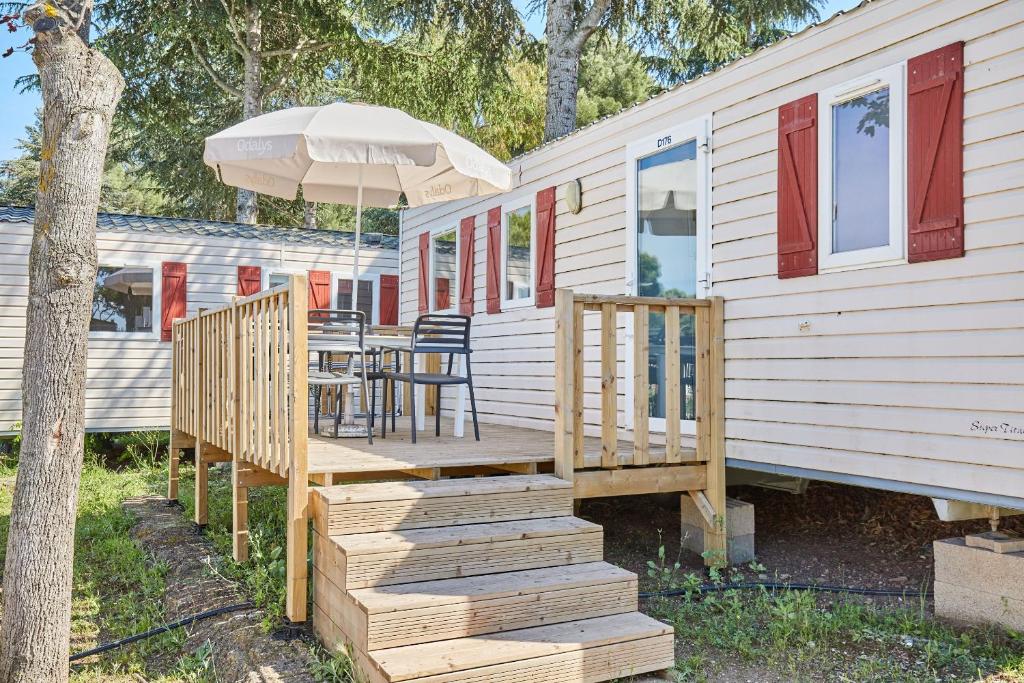 une terrasse couverte d'une maison avec une table et un parasol dans l'établissement Domaine Résidentiel de Plein Air Odalys La Pinède, à Agde