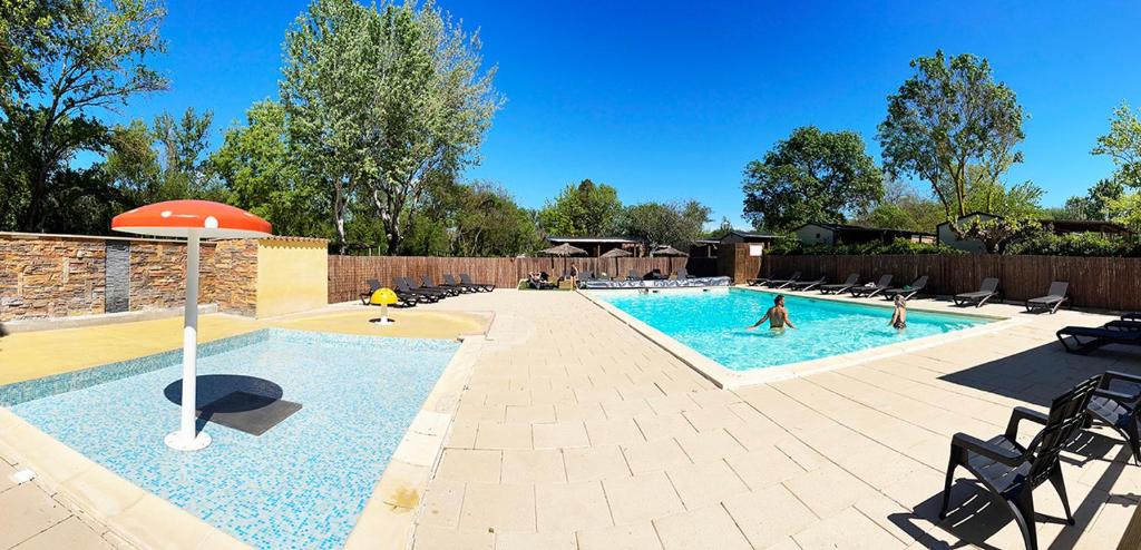 - une piscine avec des chaises et des personnes y jouant dans l'établissement Camping Le Val de Cesse, à Mirepeisset