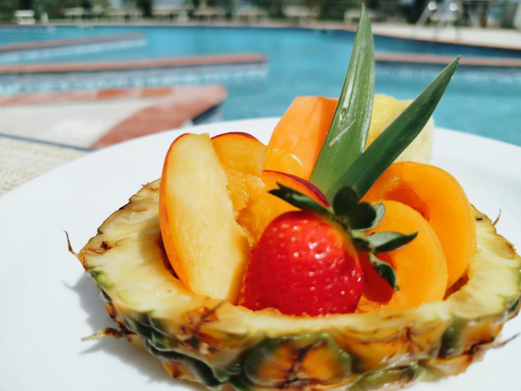 une salade de fruits dans une assiette au bord d'une piscine dans l'établissement Stella Maris Hotel, à Marina di Ginosa