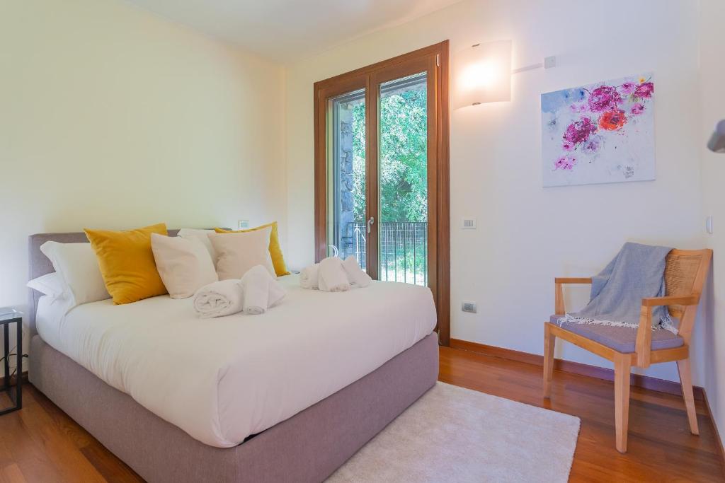 une chambre avec un grand lit blanc et une chaise dans l'établissement Villa Infinity Lake Como by Rent All Como, à Côme