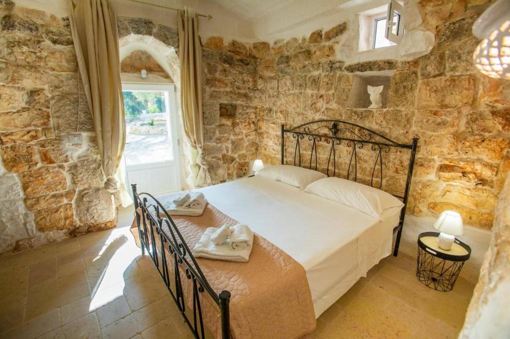 une chambre avec un lit dans un mur de pierre dans l'établissement Villa La Pagghiara by Villa Plus, à Carovigno