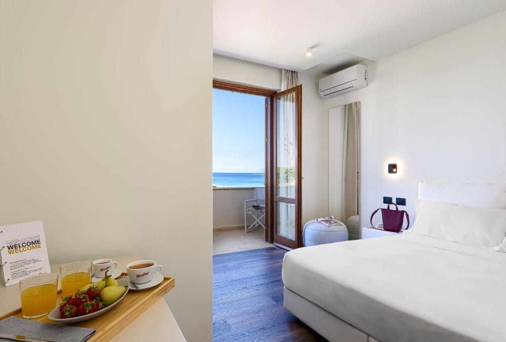 une chambre d'hôtel avec un lit et une table avec un bol de fruits dans l'établissement Albergo Auralba, à San Vito Lo Capo