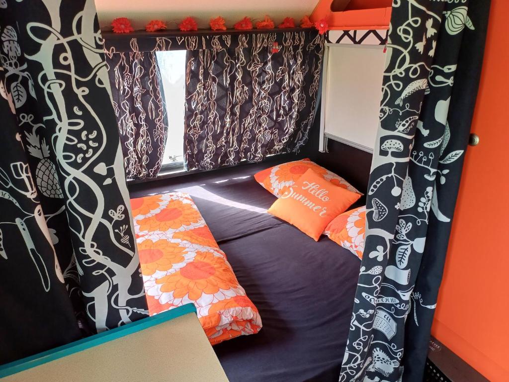 - un petit lit dans une petite chambre avec des rideaux dans l'établissement Pays de Joie - Caravan La Bohème, à Saint-Macoux