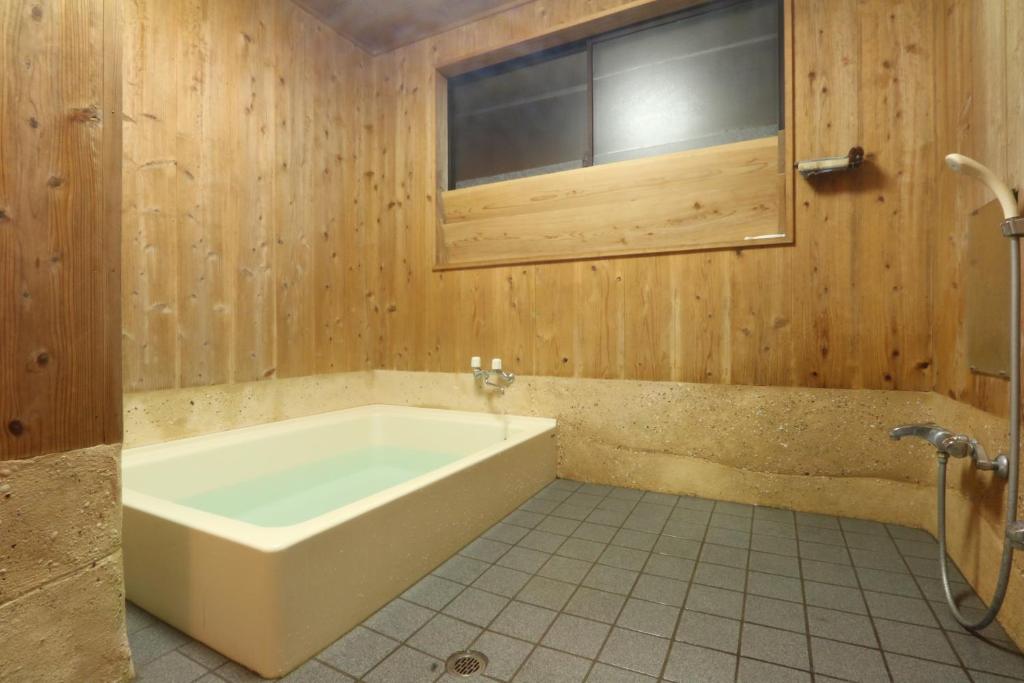 La salle de bains est pourvue d'une baignoire et d'une fenêtre. dans l'établissement Tanegashima Minshuku Yuyu, à Minamitane