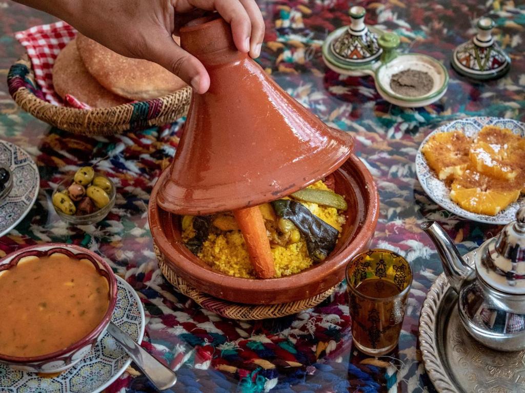 une personne tenant un pot de nourriture sur une table dans l'établissement Riad Lalla Marrakech, à Marrakech
