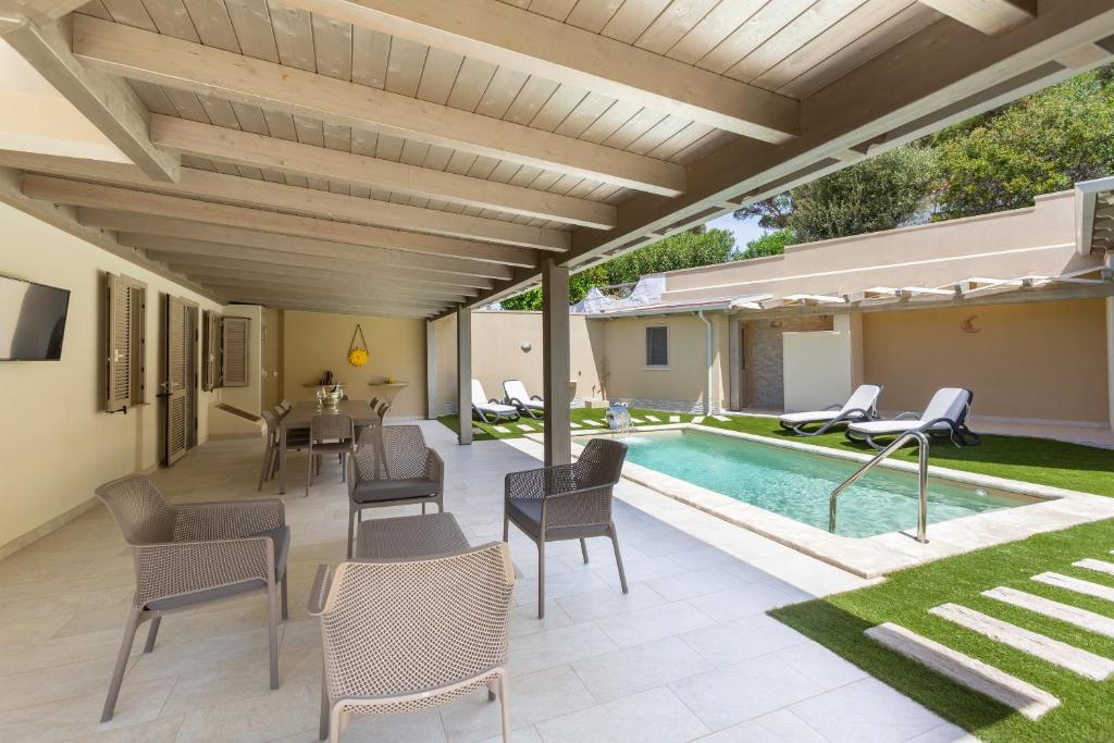 un patio extérieur avec une table et des chaises ainsi qu'une piscine dans l'établissement Villa Rachele 2 private pools, à Porto Pino