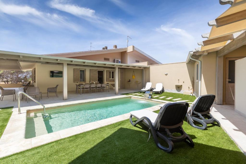 une maison avec une piscine et deux chaises dans l'établissement Villa Rachele 2 private pools, à Porto Pino