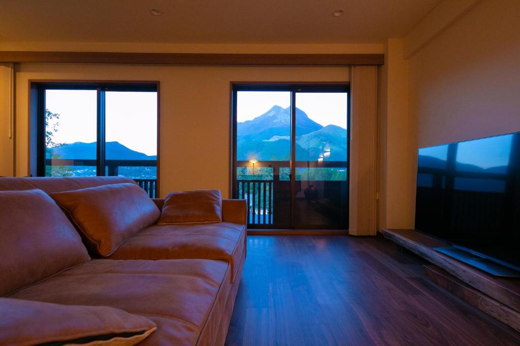 un salon avec un canapé et une télévision à écran plat dans l'établissement Saigakukan, à Yufu