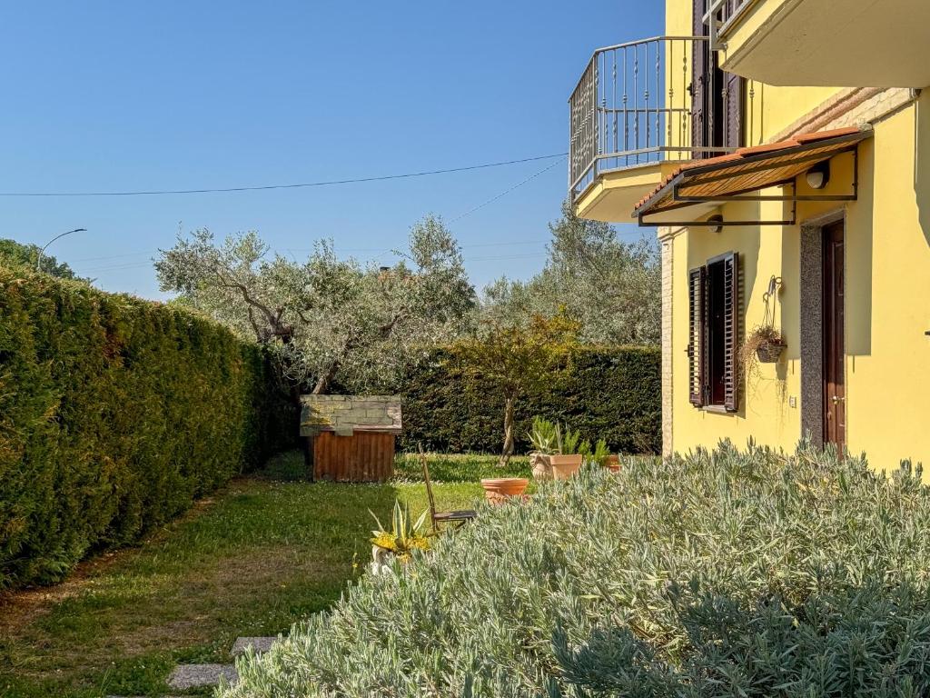 une maison jaune avec une haie à côté d'une cour dans l'établissement Casa dello Psiconauta - Atelier con giardino mediterraneo, à San Vito Chietino