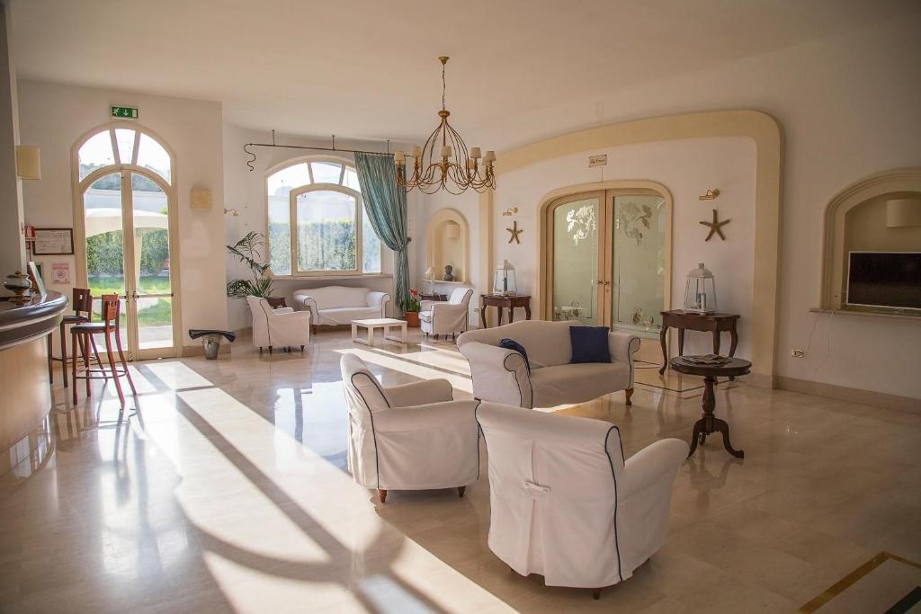 un grand salon avec des tables et des chaises blanches dans l'établissement Nicolaus Prime Il Gabbiano Hotel, à Pulsano