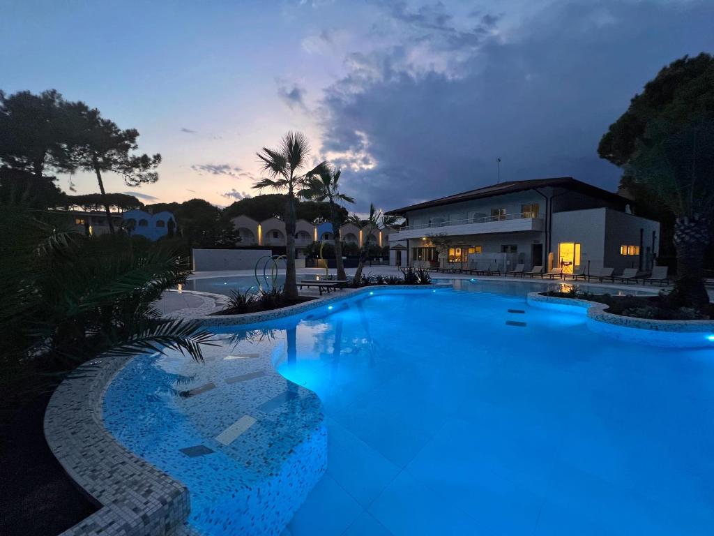 une grande piscine avec éclairage bleu en face d'une maison dans l'établissement Dune Dependance, à Bibione