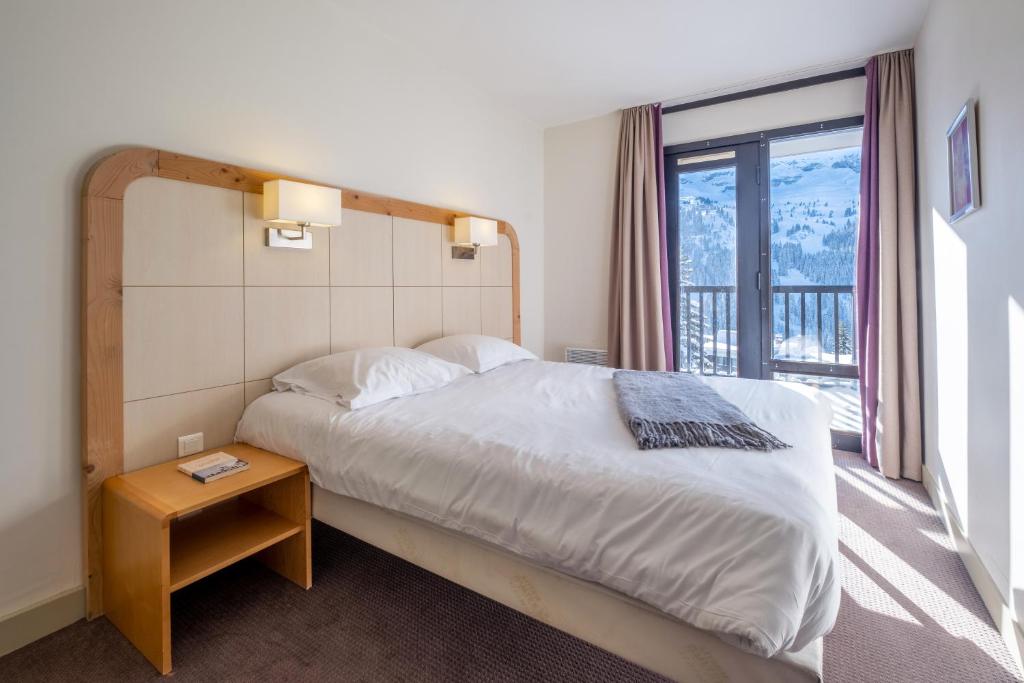 une chambre avec un lit et une grande fenêtre dans l'établissement Résidence Pierre & Vacances La Forêt, à Flaine