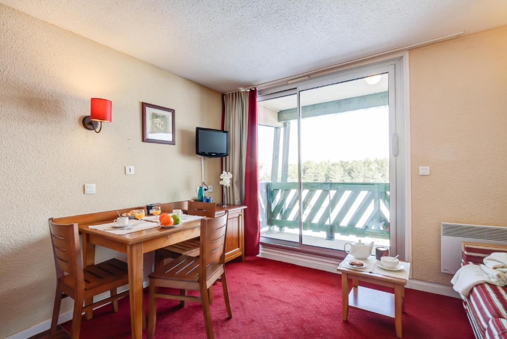 une pièce avec une table, des chaises et une fenêtre dans l'établissement Résidence Pierre & Vacances Pyrenees 2000 Le Séquoia, à Bolquère-Pyrénées 2000