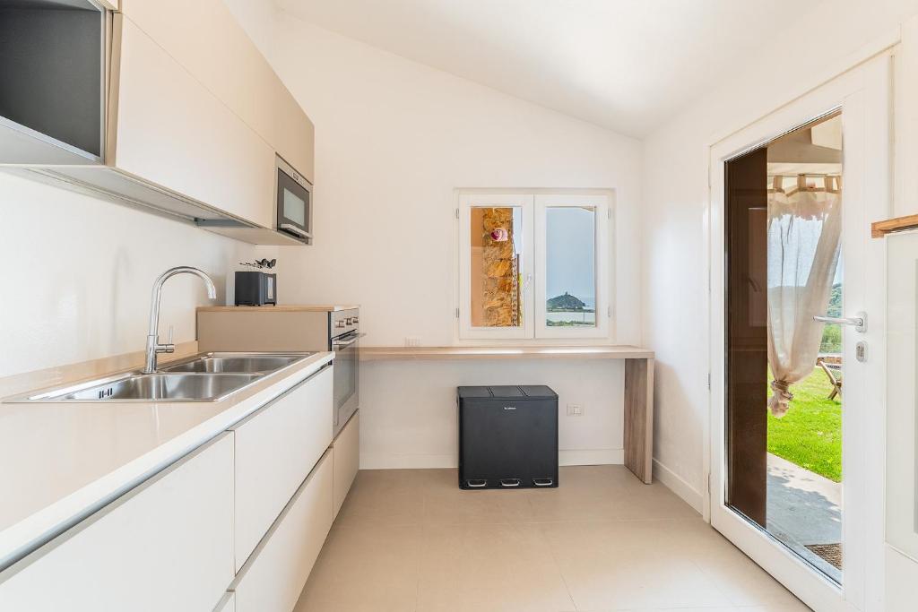 une cuisine blanche avec un évier et une fenêtre dans l'établissement Lux Villa Palma, Chia, à Chia 24 autres photos