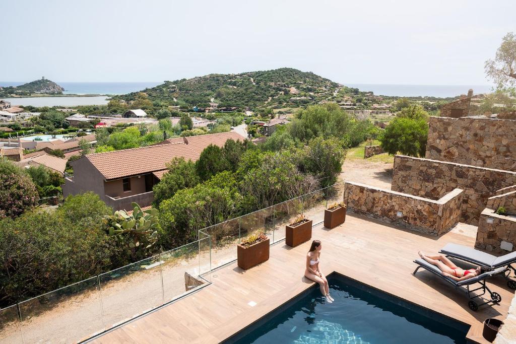 une femme se tient au bord d'une piscine dans l'établissement Lux Villa Palma, Chia, à Chia