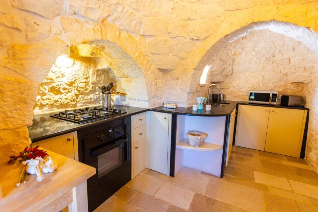 une cuisine avec un mur en pierre avec une cuisinière et un évier dans l'établissement Villa Trullo Selva Piccolo by Villa Plus, à Martina Franca