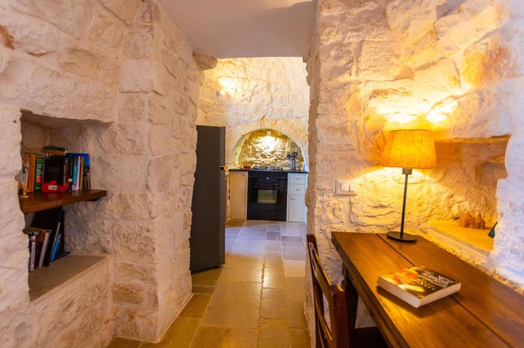 Cette chambre est dotée d'un mur en pierre et d'une table en bois. dans l'établissement Villa Trullo Selva Piccolo by Villa Plus, à Martina Franca