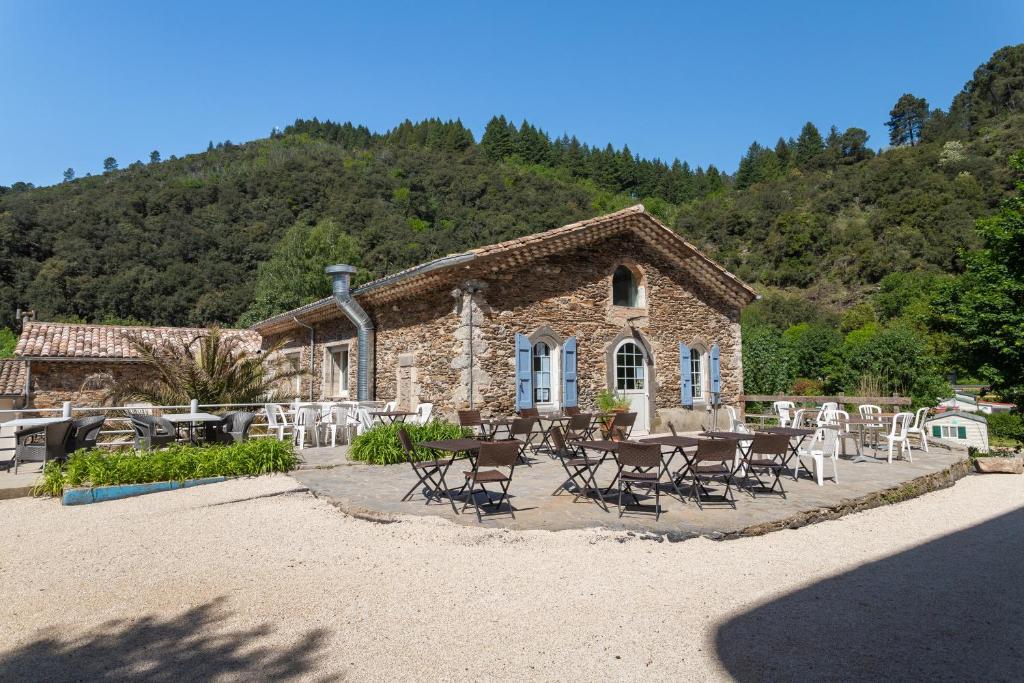 - un bâtiment en pierre avec des tables et des chaises devant dans l'établissement Château de l'Hom, à LʼEstréchure