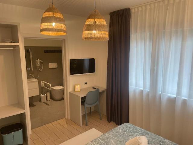une chambre avec un lit et un bureau et une pièce dans l'établissement Hotel La Pergola di Venezia, sur le Lido de Venise