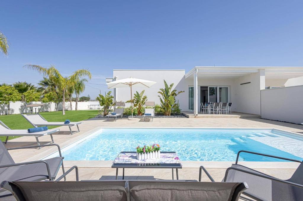 - une piscine avec des chaises et une table à côté d'une maison dans l'établissement Villa Ares by Villa Plus, à Santa Maria Del Focallo
