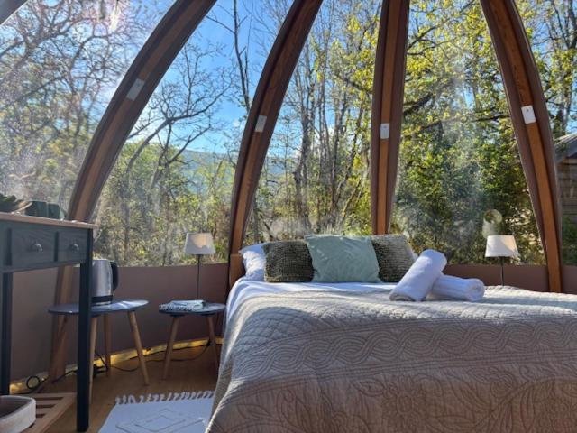 un lit dans une chambre avec une grande fenêtre dans l'établissement Wigwam et Dôdome sous les étoiles, à Champfromier