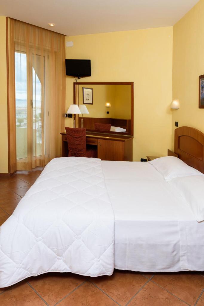 Cette chambre comprend un grand lit blanc et un bureau. dans l'établissement Hotel Audi Frontemare, à Rimini 49 autres photos