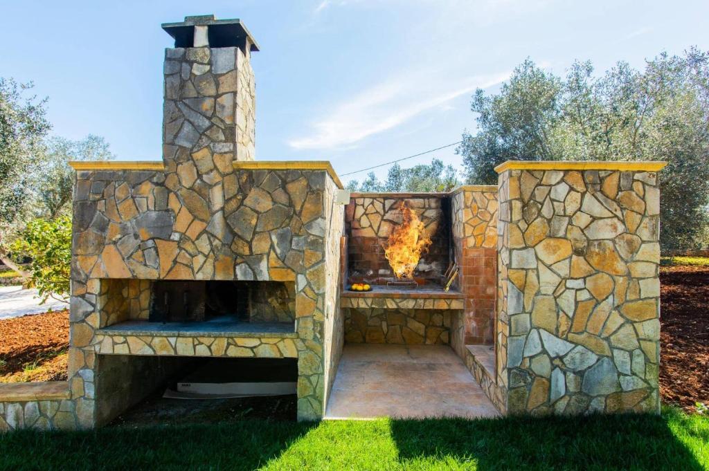 une cheminée en pierre dans une cour avec un foyer dans l'établissement Villa Maria Rosaria by Villa Plus, à Ceglie Messapica