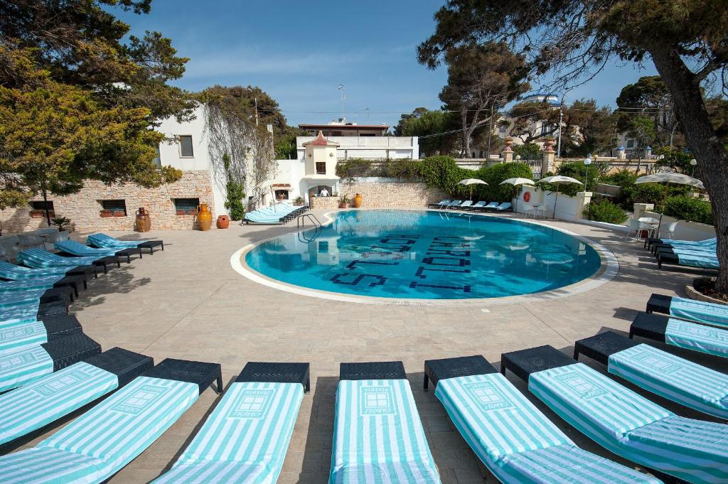 une piscine avec des chaises longues bleues et blanches dans l'établissement Hotel Terminal - Caroli Hotels, à Leuca