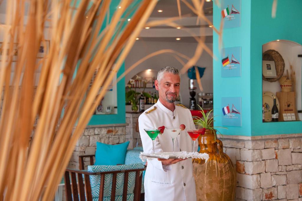 un homme tenant un plateau avec deux cocktails dans l'établissement Hotel Terminal - Caroli Hotels, à Leuca 141 autres photos