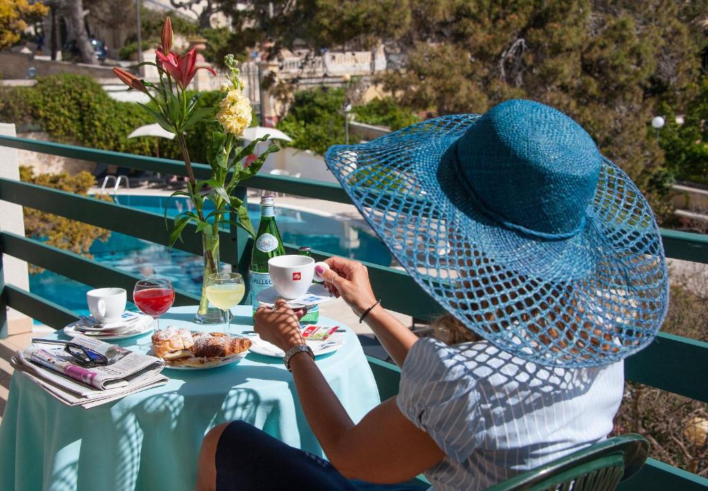une femme assise à une table avec une tasse de café dans l'établissement Hotel Terminal - Caroli Hotels, à Leuca