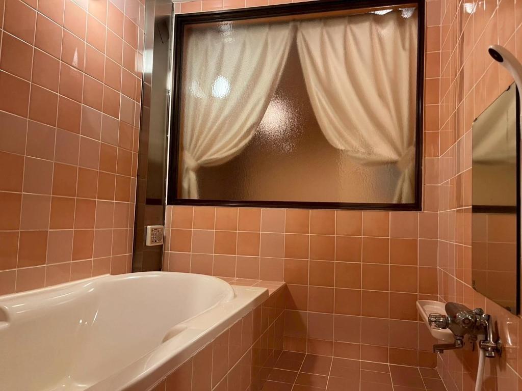 une salle de bain avec une baignoire, un lavabo et une fenêtre dans l'établissement ホテル リトリート Hotel retreat, à Sado