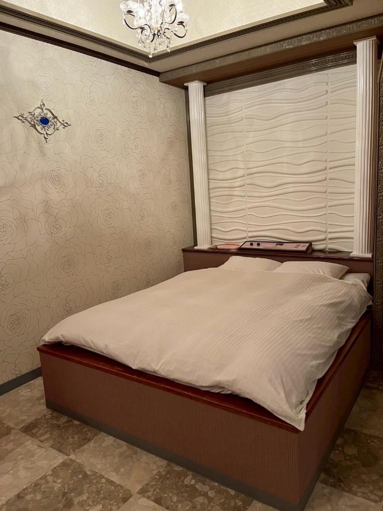 - une chambre avec un lit, une fenêtre et un lustre dans l'établissement ホテル リトリート Hotel retreat, à Sado