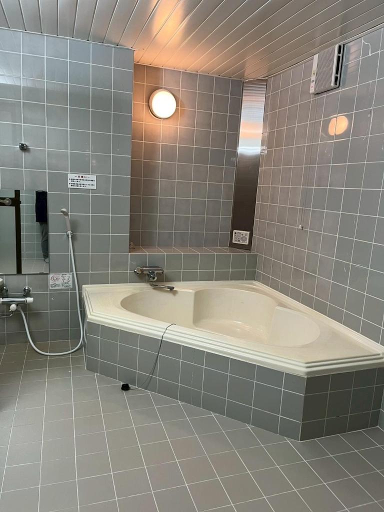 La salle de bains est pourvue d'une baignoire et d'un miroir. dans l'établissement ホテル リトリート Hotel retreat, à Sado