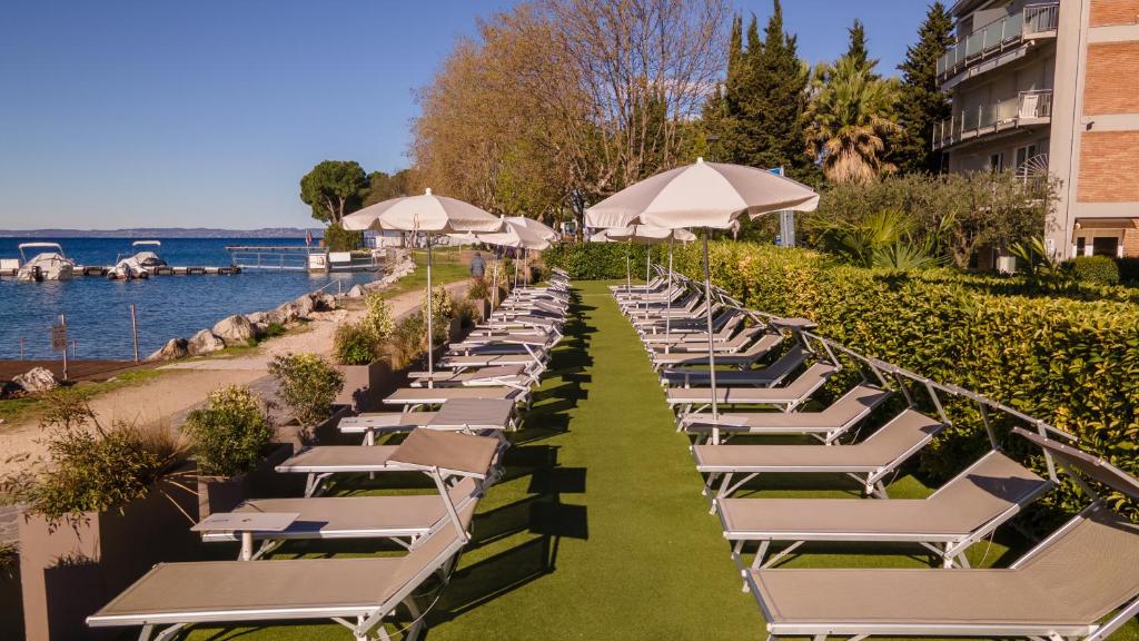 une rangée de chaises longues et de parasols dans un complexe hôtelier dans l'établissement Kriss Internazionale Hotel, à Bardolino