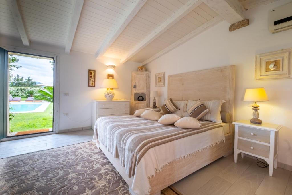 une chambre avec un grand lit et une grande fenêtre dans l'établissement Luxury Villa Porto Rotondo with private pool by Varental, à Porto Rotondo