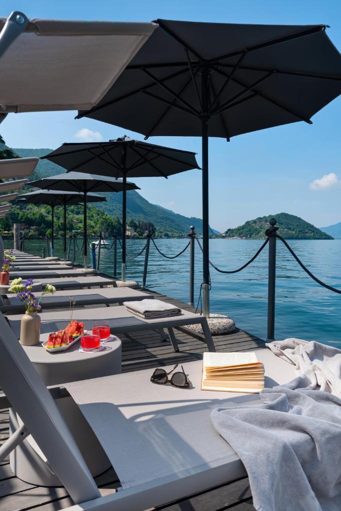 une rangée de tables avec des parasols sur l'eau dans l'établissement Hotel Rivalago, à Sulzano
