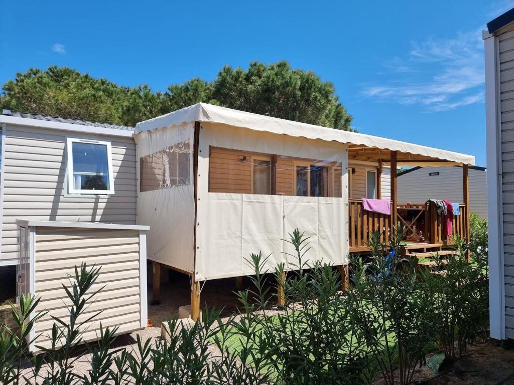 une grande maison blanche avec un toit dans l'établissement Kokua Vacances présente MOBIL HOME résidentiel toutes options camping 4 étoiles CANET, à Canet